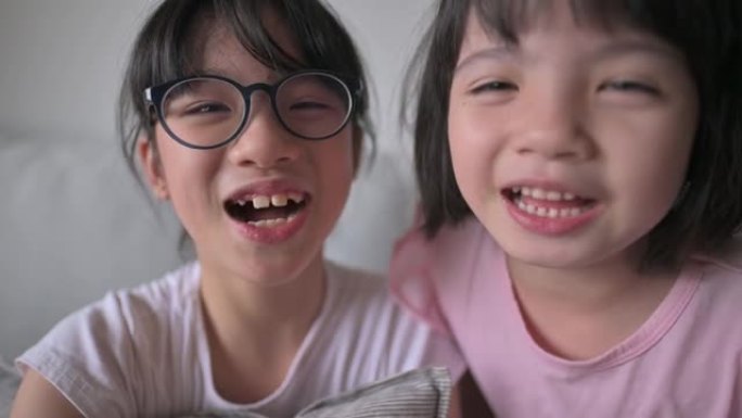 亚洲华裔年轻女孩在沙发上的客厅在线使用数字平板电脑与父亲交谈