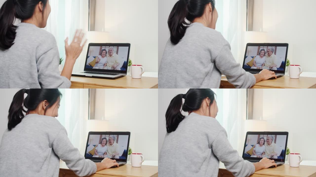 年轻的亚洲商界女性使用笔记本电脑视频通话，与家人爸爸和妈妈在床上工作。