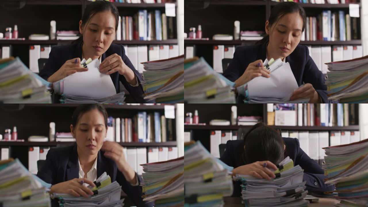 亚洲年轻女性在工作到很晚的办公桌上睡觉时过度劳累