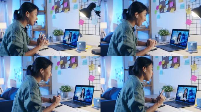 亚洲女商人使用笔记本电脑与同事讨论客厅视频通话会议的计划。