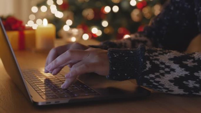 在舒适的家中，在笔记本电脑电子贺卡上打字圣诞快乐。