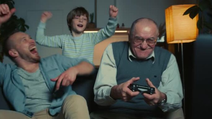 家庭交往时间。快乐兴奋的父亲、十几岁的儿子和高级祖父在家里玩游戏机玩得很开心。