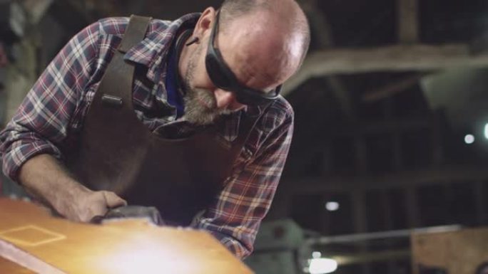 男性铁匠戴着安全眼镜，使用等离子切割机从锻造的钣金切割形状