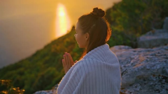 在悬崖上祈祷姿势冥想的年轻女子