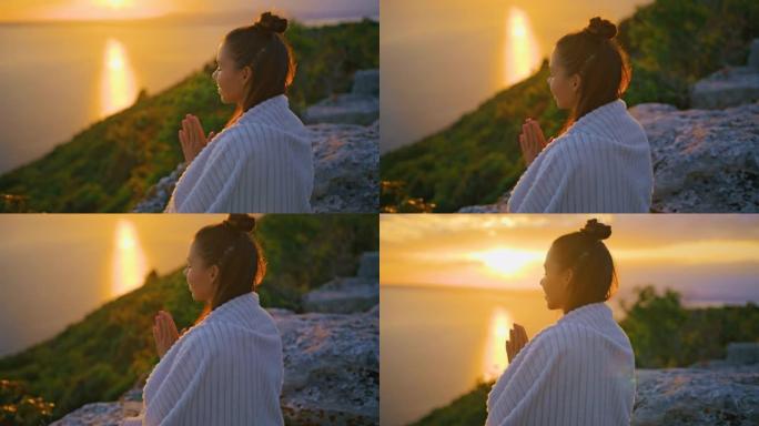 在悬崖上祈祷姿势冥想的年轻女子