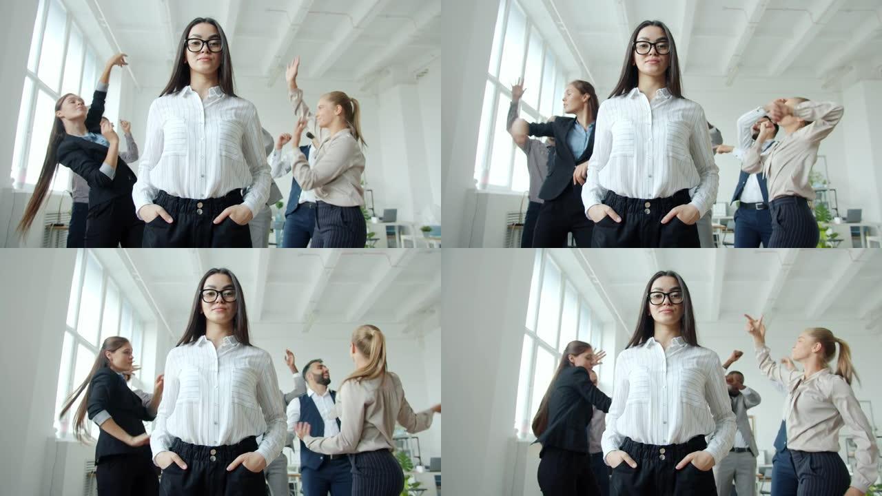 年轻的亚洲女商人面容严肃地站在办公室里，男人和女人在跳舞