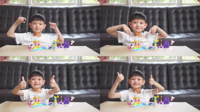 亚洲小男孩在家时在客厅展示模塑粘土制作工艺品。他完成了五颜六色的橡皮泥的塑造，创造了一个玩具艺术项目