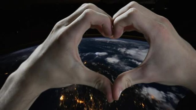双手在太空中的地球上形成心脏。NASA提供的这段视频的元素。