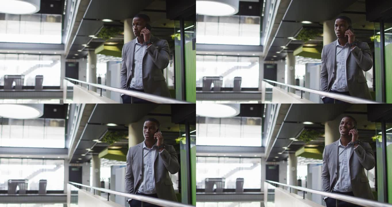 非裔美国商人在现代办公室的走廊上谈论智能手机