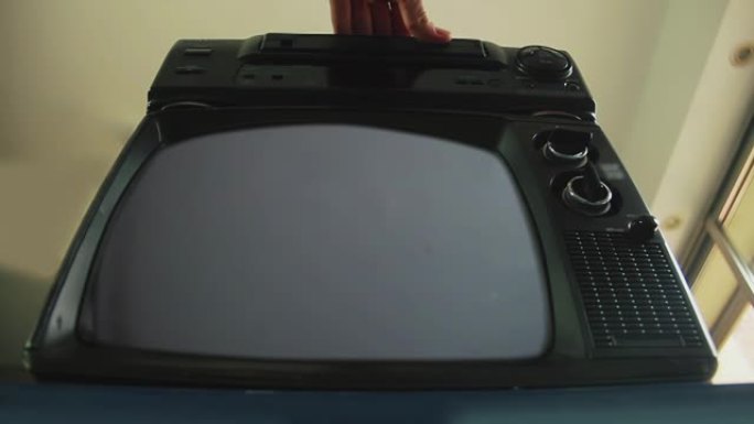 用手将VHS盒式磁带插入旧录像机中，复古电视打开绿色屏幕。低角度视图。4k分辨率。