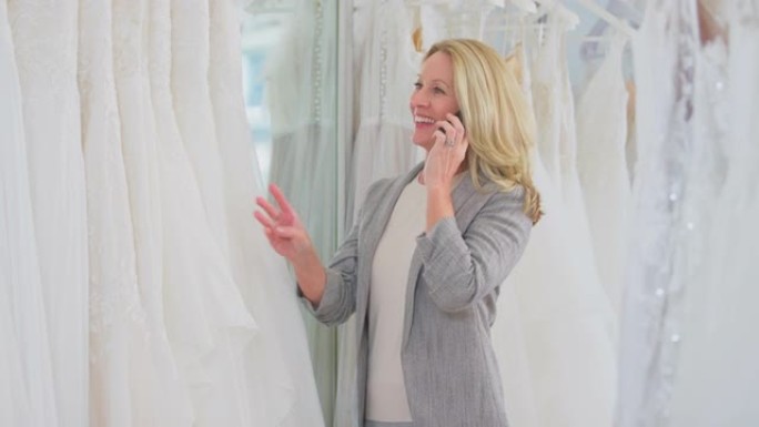 新娘商店的成熟女性老板在手机上聊天，在手机上聊天-慢动作拍摄