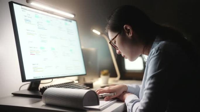 亚洲女商人做笔记，晚上在办公室用电脑工作，聚焦概念