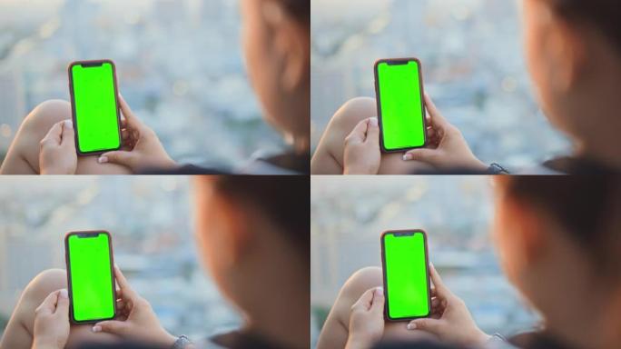女人在屋顶露台上使用色键绿屏智能手机，跟踪镜头