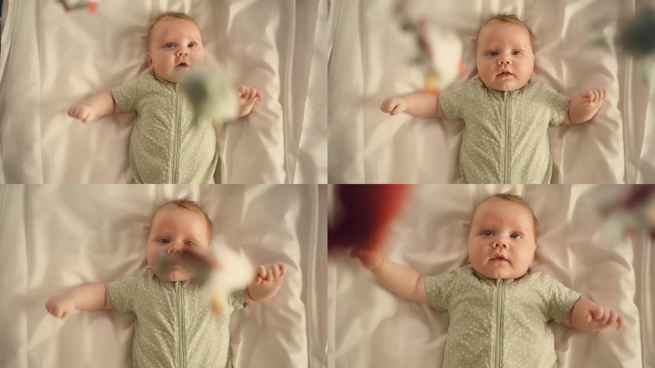 美丽的特写镜头，一个可爱的新生婴儿躺在婴儿床的背上。一个兴奋的幼儿看着旋转的玩具的嬉戏肖像。童年、新
