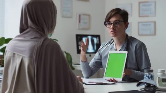 自信的医生用平板电脑向穆斯林女性患者做介绍