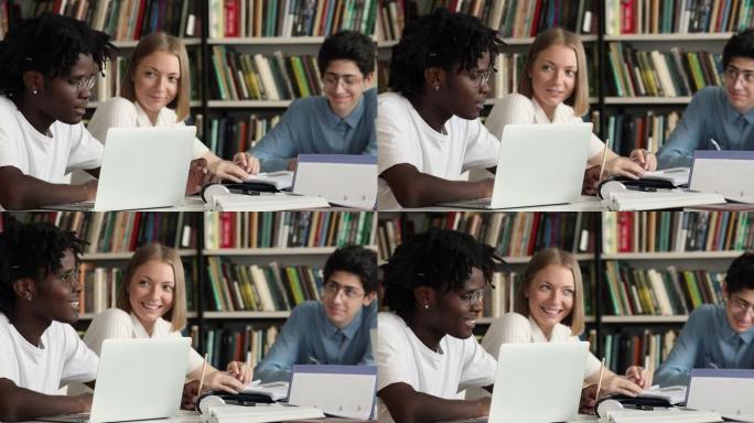 多样化的学生坐在图书馆的办公桌前准备考试