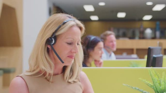 戴着耳机与客户服务中心呼叫者交谈的成熟女商人肖像