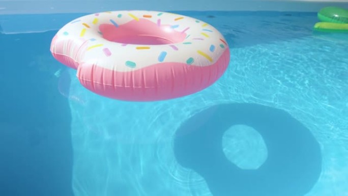 特写: 彩色充气玩具漂浮在空荡荡的水上彩色游泳池周围。