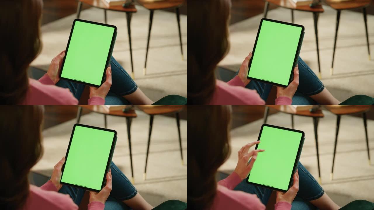 女性在带有绿屏模拟显示的平板电脑上滚动和点击内容。女人在家放松，在移动设备上阅读社交媒体帖子。特写镜