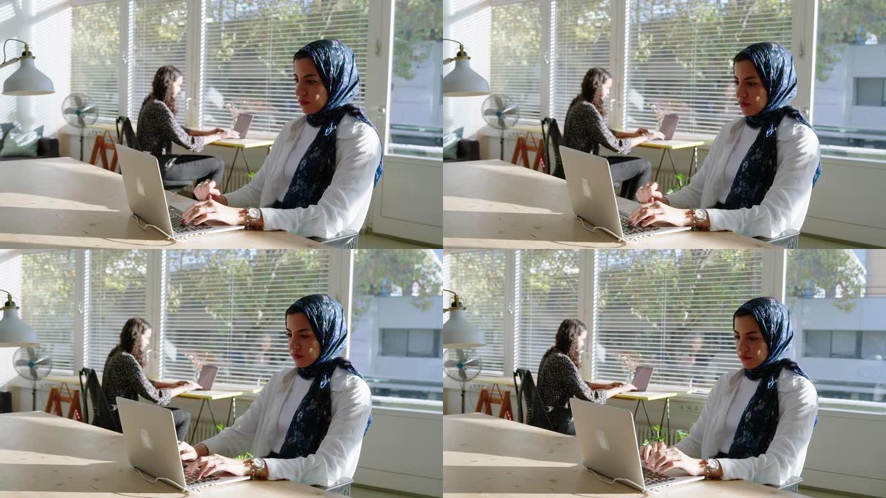 中东女商人带着头巾在启动工作区的笔记本电脑上工作