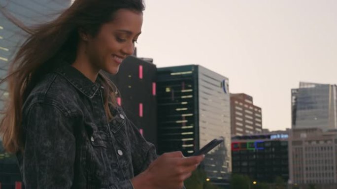 4k视频片段，一名年轻女子在城市的屋顶上使用手机