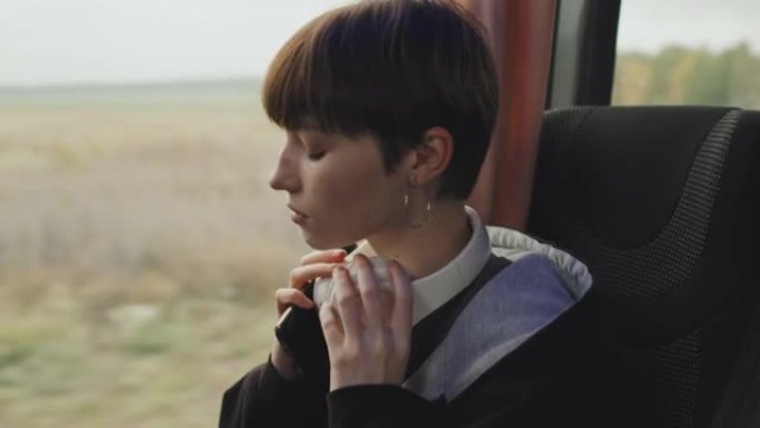 戴着耳机的少女坐在公共汽车的窗户旁