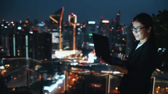 年轻的亚洲妇女在屋顶和笔记本电脑上工作