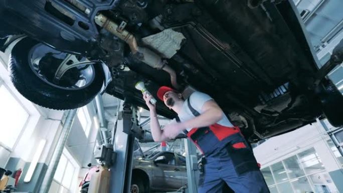 汽车修理工用手电筒检查车辆的底面。汽车、汽车服务理念。