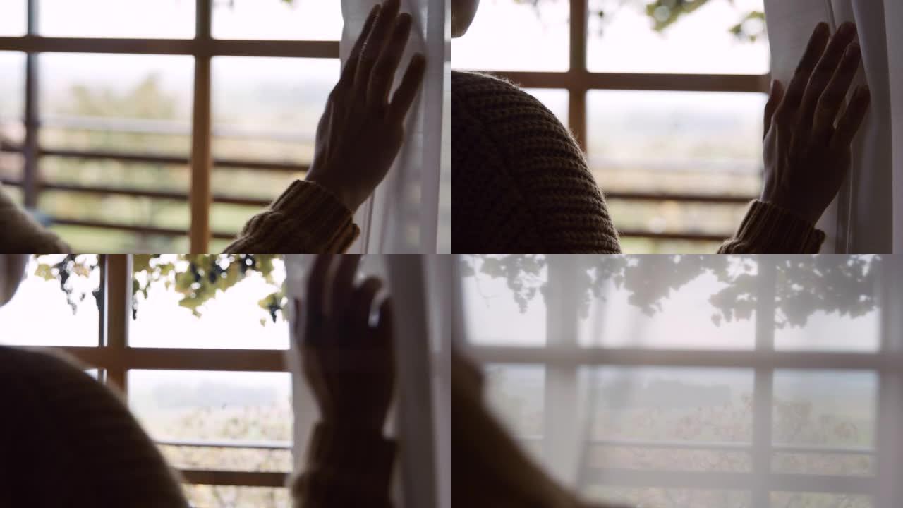 SLO MO无法识别的女人将窗帘移到侧面，这样她就可以在窗外看一眼