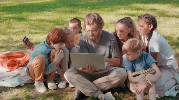 一群带笔记本电脑的孩子和老师在公园