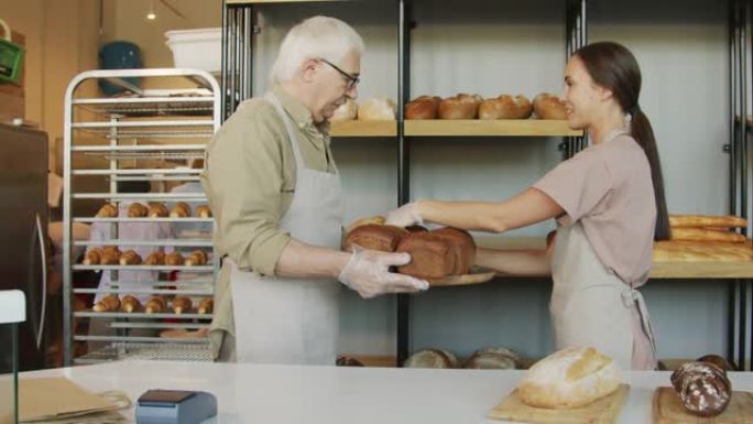 人们将新鲜出炉的面包放在面包店的架子上