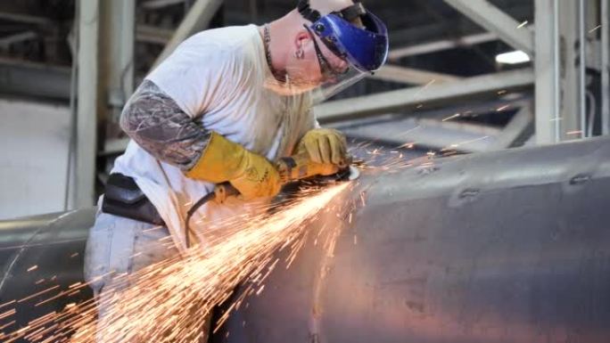 金属工人在工厂的大圆筒上使用研磨机