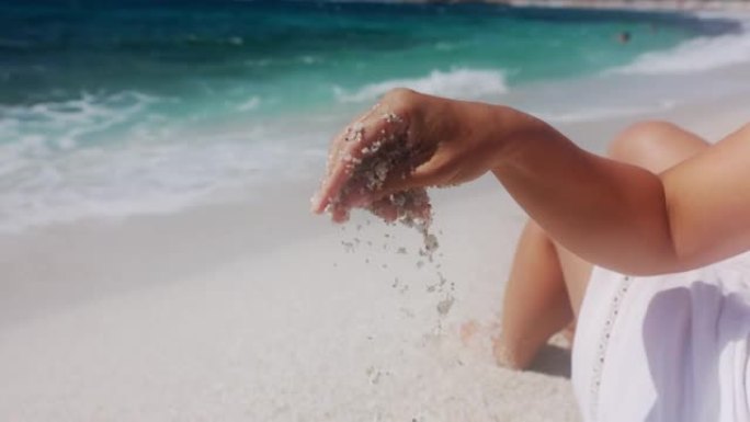 女人的手在海滩上玩沙子的景色，意大利。