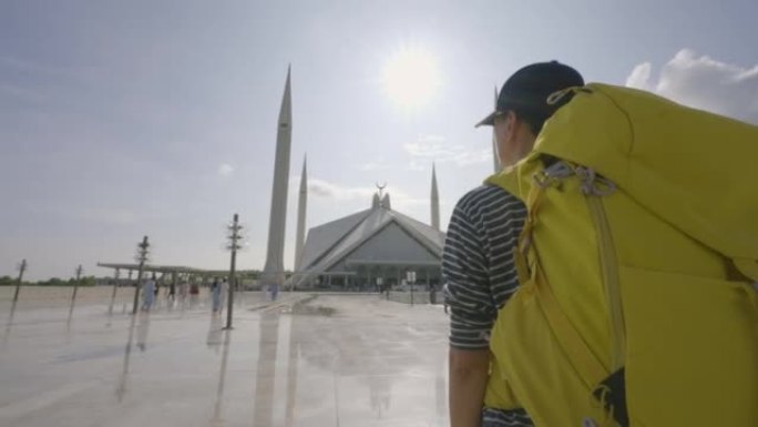 自由旅行者年轻女性背着黄色背包散步，看着旅游假期的令人惊叹的清真寺。种族多样化的旅行者概念。与阿尔法