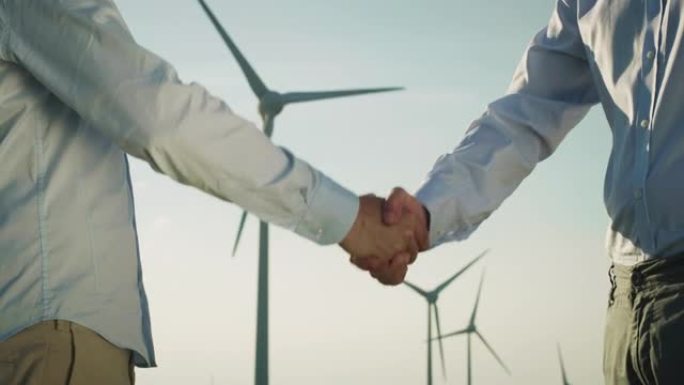在达成有关风电场建设的协议后，两个合作伙伴握手。两名男性成年人同意为子孙后代建立更好的生态友好环境