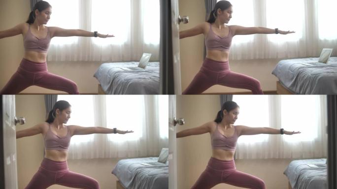 年轻的亚洲妇女在家里的卧室里练习瑜伽