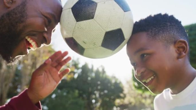 非裔美国人父亲和儿子在花园里用头平衡足球