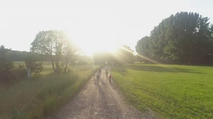 有三个孩子的空中家庭在一条土路上骑自行车