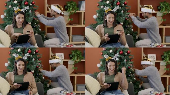 4k视频片段，一名妇女使用数字平板电脑在圣诞节最后一刻购物，而丈夫则在家里装饰树