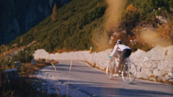 骑自行车的人在阳光明媚的山路上骑自行车
