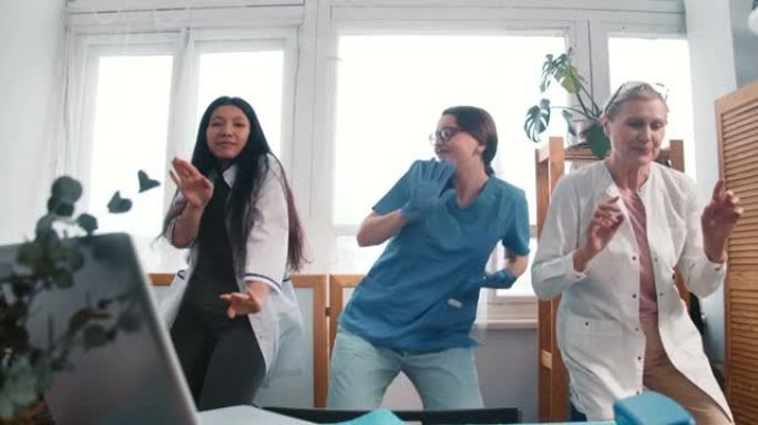 放大三位有趣的快乐科学家女医生在诊所实验室跳舞庆祝战胜大流行。