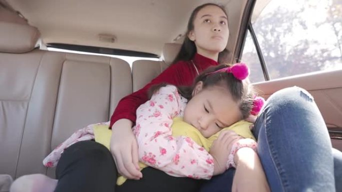 可爱的亚洲小女孩和她的妹妹在汽车座椅的后面
