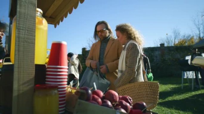 夫妇站在摊位上，摆着水果和蔬菜