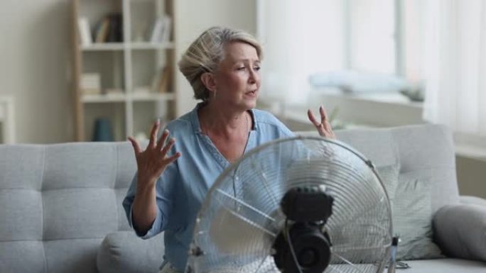 过热的60年代妇女使用便携式地板电风扇冷却自己