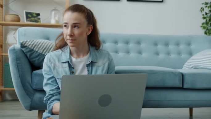 坐在家里地板上的漂亮年轻女子用笔记本电脑慢动作