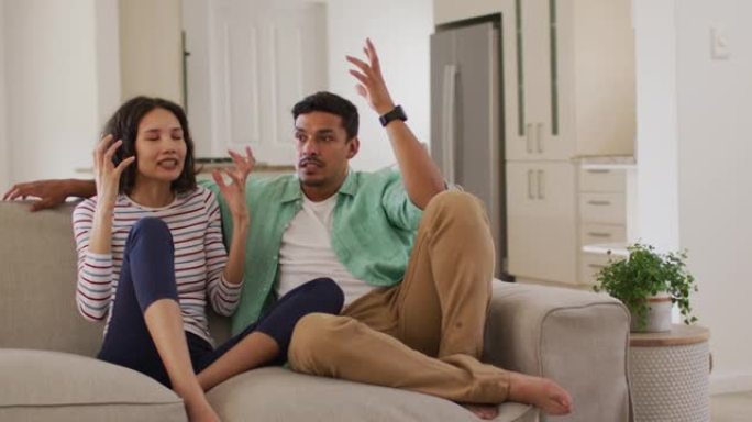 愤怒的西班牙裔父母坐在沙发上争论着跳舞的女儿