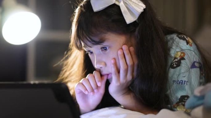 小女孩在家睡觉前在数字平板电脑上看卡通