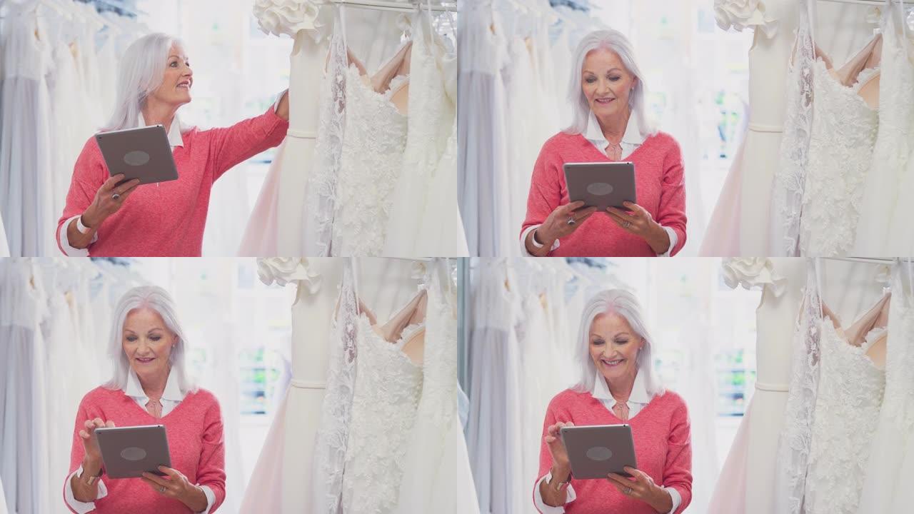 新娘商店的女老板拿着数码平板电脑看着婚纱-慢动作拍摄