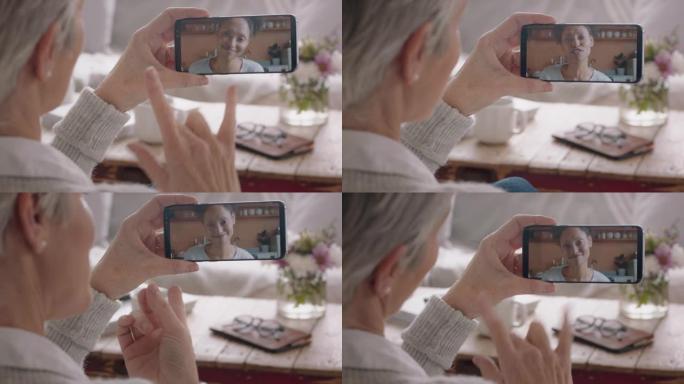 成熟的女人使用智能手机进行视频聊天聋哑的母亲用手语与女儿聊天享受与家人在手机上的对话听力受损的交流