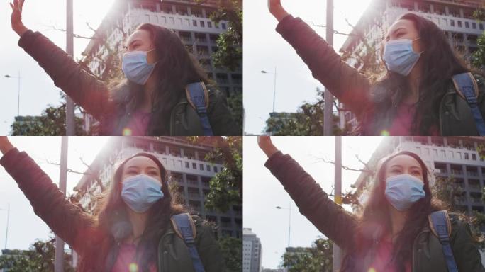 亚洲妇女戴着口罩在街上叫车时站在街上